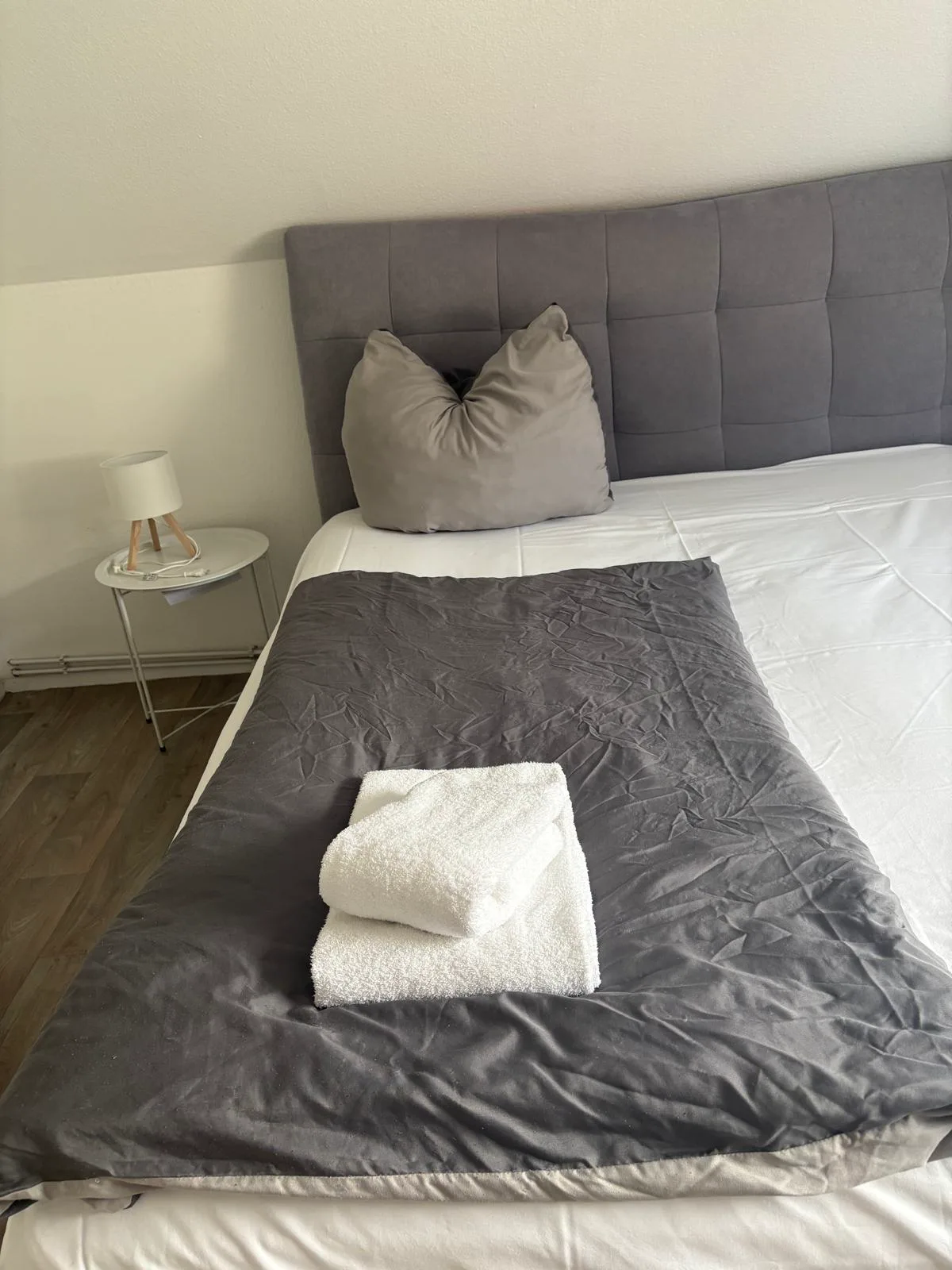 Bezugsfertig vorbereitetes Schlafzimmer mit frischer Bettwäsche und Handtüchern